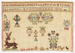  An antique embroidered sampler featuring two alphabets and a row of numbers at the top followed by decorative motifs including symmetrical floral and heart patterns and a large deer on the bottom left, with the date "1801" stitched in the center. The colors are subdued with varying shades of brown, red, blue, green, and gold, indicating age and wear.