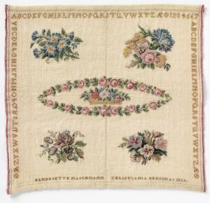  An embroidered sampler featuring alphabets and numbers in a brownish hue around the edges, with four symmetric floral bouquets in each corner and a diamond-shaped floral medallion in the center, set against a pale beige background with a border stitch, and dated 1863.