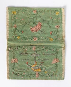  A vintage emerald green textile, possibly a book cover or pouch, with delicate floral embroidery in shades of pink, red, yellow, and brown, bordered by a light beige trim against a neutral gray background. The textile shows signs of age with slight fading and wrinkling.