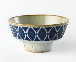  A ceramic bowl with a cobalt blue exterior featuring an intricate pattern of interlocking circles and lighter blue motifs, accented by a golden-yellow rim, and a warm, pale golden-glazed interior.