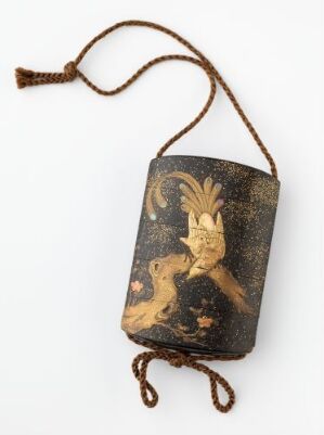  An antique, painted wooden pendant with a golden rabbit and crescent moon motif on a dark, aged background, complete with a brown braided cord for hanging.