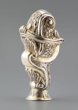  An intricate gold-toned metallic object with baroque or rococo style decorations, featuring fluid swirls, and leaf-like patterns, possibly resembling a stylized scroll or floral form, with an "S" shaped top and a rounded base. Artistname and title are unknown.