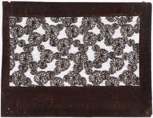  An intricately patterned rectangular object, possibly textile, with a repeating black floral motif centered within a textured brown border that may resemble leather.