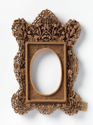  An detailed oval picture frame with intricate floral designs in a warm golden brown tone, set against a light grey background, with no picture enclosed.