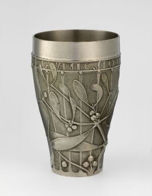  A pewter-colored metallic cup with Art Nouveau style embossed decoration featuring stylized plants and flowing lines, tapering slightly from a wider polished rim to a narrower base.