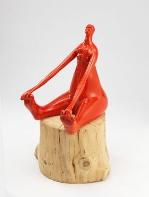  "Prins nr. 2," a sculpture by Irene Nordli, depicting a reflective, bright red humanoid ceramic figure posed atop a natural wooden stump with visible grain and knots, showcasing a contrast in materials and colors.