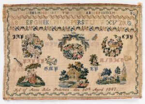  An aged sampler embroidered with a cream background featuring symmetrical designs; including a row of dark-toned letters and numbers, four floral wreaths with multi-colored flowers, and a pastoral scene with a figure, trees, shrubs, and an animal in more muted tones. There is woven text that reads "Lief van Oukje Rienks spannen Januar 22 1867," indicating