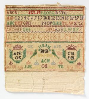  An antique embroidery sampler featuring multiple rows of alphabet letters in upper and lower case, along with numerals 1-16, stitched in red and green thread on cream fabric. Decorative borders and symmetrical plant motifs separate the rows, and frayed edges suggest an aged and vintage textile piece.