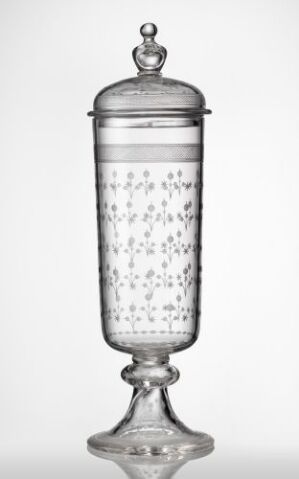  A clear glass cylindrical container with a lid, decorated with numerous small bubbles within the glass, standing against a light background. Artistname and title are unknown.