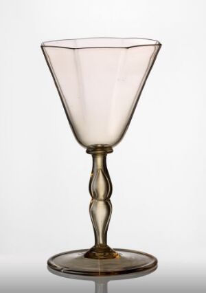  A delicate glass goblet with a wide, slightly tapered bowl with a pinkish hue, an elegantly designed stem with bulbous sections, and a round, flat base with a subtle amber tint, set against a neutral background. Artist name and title are unknown.