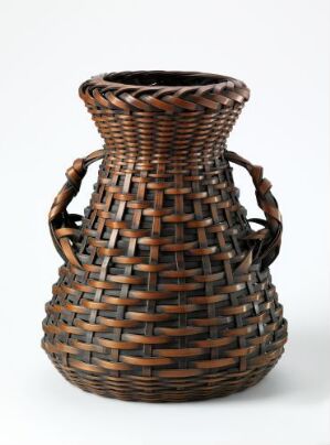  A crafted woven basket with a bulbous body, flared top, darker rim, and two arching handles, showcasing intricate weaving patterns in natural brown tones against a white background. Artist name and title are unknown.