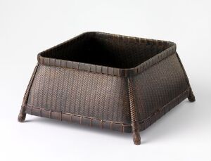  A square woven basket with a dark brown color and intricate herringbone pattern, featuring slightly slanted sides that flare out and then turn inward, with reinforced corners set against a plain background. Artist name and title are unknown.