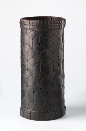  A cylindrical dark brown object with a textured diamond pattern surface against a light grey background, suggesting a decorative vase or crafted container. Artist name and title are unknown.