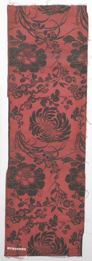  A long, vertical textile piece with a complex, symmetrical floral and scrollwork pattern in shades of deep red and black, suggesting a luxurious baroque or rococo style. The material and technique are unidentified, and the artist's name is unknown.