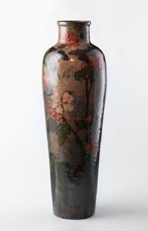  A tall, slender ceramic vase with a glossy finish, featuring a hand-painted floral pattern in muted shades of brown, red, and green against a plain background. The artistname and title are unknown.