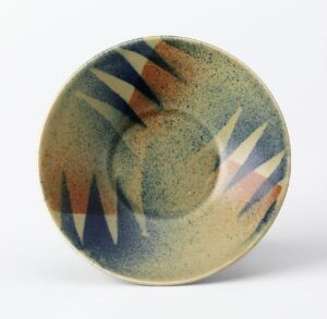  A shallow, wheel-thrown glazed bowl from Egersunds Fayancefabrik, decorated with a sprayed blue and brown abstract geometric pattern on a greenish-blue speckled background. The design features dynamic triangles and lines emanating from the center.