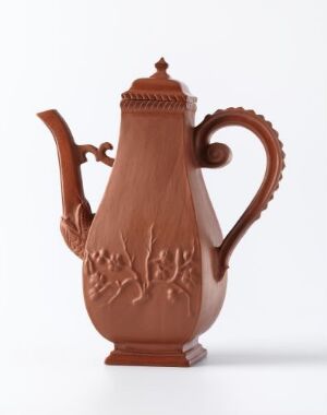  A terracotta coffee pot with elaborate handle and spout, featuring a low-relief floral design, set against a white background.