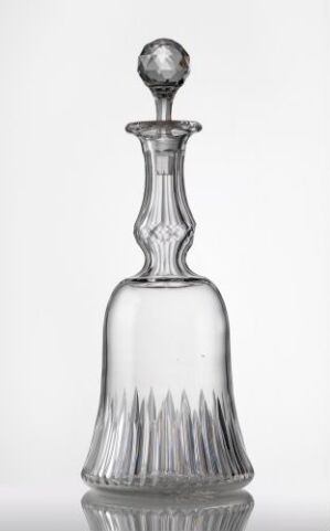  A clear glass decanter with a fluted base and a round stopper set against a white background, showcasing its elegant design and transparent material.