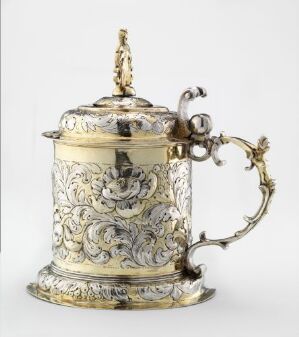  Silver drinking vessel titled 'Drikkekanne' by an unidentified artist, featuring intricate relief patterns and gold accents, displaying elaborate craftsmanship and artistry on its surface.