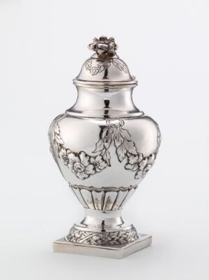  An antique silver urn with ornamental designs on a square base, featuring a domed lid topped with a decorative finial, set against a light-gray background. Artist name and title are unknown.