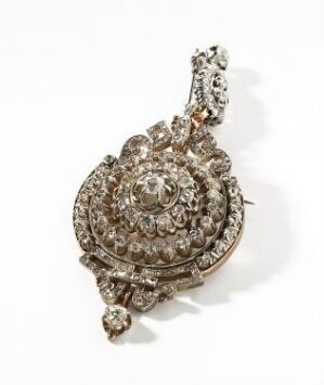  An intricate brooch or pendant composed of multiple round, faceted gemstones set in a metallic frame, with a large central stone surrounded by layers of smaller stones in a floral-like pattern, against a plain, light background.