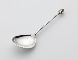  A silver spoon titled "Sølvskje" by an unidentified artist, featuring a polished, reflective bowl and an elegantly patterned handle with a decorative motif at the end. The spoon is set against a neutral background, highlighting its gleaming silver surface and detailed engravings.