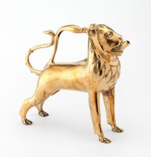  An intricately designed brass "Akvamanile" in the shape of a standing lion with a glossy, golden finish, detailed engraving, and a background that fades to off-white. Artist unknown.