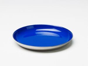  A round, shallow dish designed by Grete Prytz Kittelsen made of stainless steel with a shiny, reflective metallic rim and a glossy ultramarine blue enamel interior.