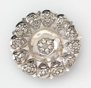  "Fat" by Niels Joensen Greger is an ornate silver tableware piece resembling a flower with a central glass bowl and detailed repoussé silver petals.