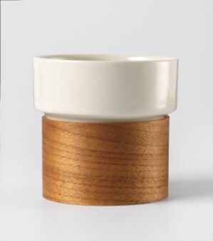  A Tonfisk Design Oy tableware piece with an unknown title, featuring a white porcelain container that fits into a round, laminated walnut wood base, displaying contrasting textures and colors.