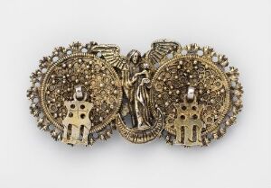  A golden, three-part hinged item that resembles an ornate brooch, featuring a central angelic figure and flanking discs with simplified human forms and elaborate textures. The artist name and title are unknown.