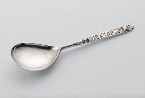  Antique silver spoon titled "Sølvskje" by Jonas Andersen, with an intricately engraved handle and a reflective bowl, set against a light gray background.