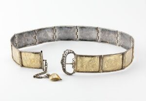  Antique belt with silver-toned rectangular panels and creamy ivory inlays, featuring an intricate horseshoe-shaped buckle with a serpent-like detail and a small heart-shaped pendant.