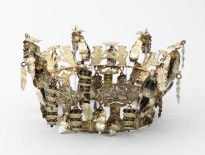  An ornate, antique-looking crown with silver and gold elements and various reflective textures sits against a neutral background, purportedly composed of metal, possibly with decorative stones or gems. Artistname and title are unknown.