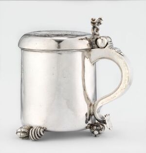  A silver tankard with an ornate handle and a hinged lid on a neutral background, exuding elegance and reflecting a well-polished surface.