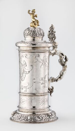  Antique silver drinking vessel "Drikkekanne" by Jakob d.y. Tores, featuring a cylindrical shape with embossed patterns, a decorative handle, and a figurine-topped lid, exhibiting luxurious craftsmanship from a bygone era.