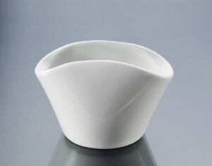  "Spir" by Johan Verde, a modern, asymmetrical white porcelain bowl with a spiraling design on a soft gray background, showcasing its sleek, molded and glazed surface.