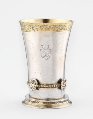  Silver drinking vessel titled "Drikkebeger" by an unidentified artist, featuring a tapered shape with golden gilded bands, an embossed shield, and intricate engravings. The piece demonstrates the artistry of driven and cast silver with gilding, soldering, punched, and engraved decorations, typical of design/kunsthåndverk and the classification of eating utensils, crafted by the technique of driving.