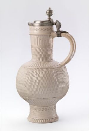  A cream-colored ceramic or porcelain beer stein with a textured body and a decorative metal lid, positioned against a plain light-gray background.