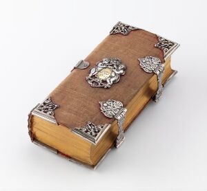  An antique religious songbook titled "Harboe's og Guldberg's Salmebog" by an unidentified artist, bounded in brown velvet with ornate, sculpted, and pierced silver decorations and clasps on the cover, exuding a sense of historical richness and artistry.