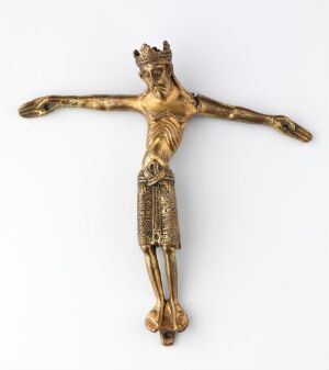  Cast and engraved brass crucifix by an unidentified artist titled "Del av krusifiks", showing a golden-hued figure of Jesus Christ with outstretched arms affixed to the cross, featuring engraved details and a crown on his head, representing the Crown of Thorns, exemplifying ecclesiastical metalwork design.