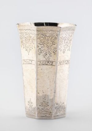  A cylindrical silver drinking cup titled "Drikkebeger" by an unidentified artist, with intricate floral and geometric engraving throughout, tapering slightly towards the base, displayed against a plain background.