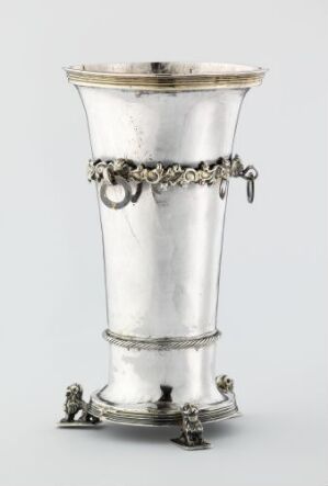  "Drikkebeger," a silver drinking vessel created by Rørich Giligsen, with a tapered cylindrical shape, ornamental band with gilded details mid-body, and decorative feet, all displayed against a neutral background.