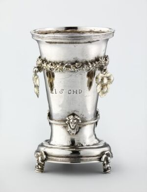  An ornate silver drinking vessel known as "Drikkebeger" by an unidentified artist, featuring detailed engravings and relief work, gleaming in shades of light gray with a refined and polished finish.