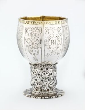  A partially gilded silver drinking vessel, named Drikkebeger, showcasing intricate floral and scrollwork patterns. The vessel's rim is gilded, while the body, stem, and foot feature detailed silver designs, all on a neutral background. Created by Jochim Haveman.