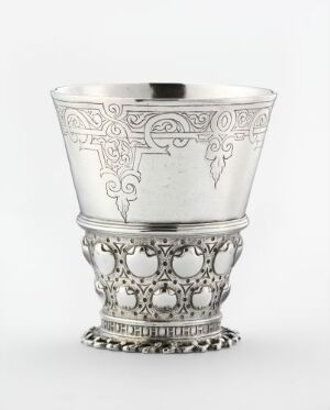  Silver drinking cup titled "Drikkebeger" by artist Hans Threkill, featuring intricate engravings, and crafted using techniques such as hammering, soldering, chiseling, punching, and engraving. The cup has a textured base with bead-like details, ornate filigree, and decorative patterns along its body, conveying a sense of historical and artisanal significance.