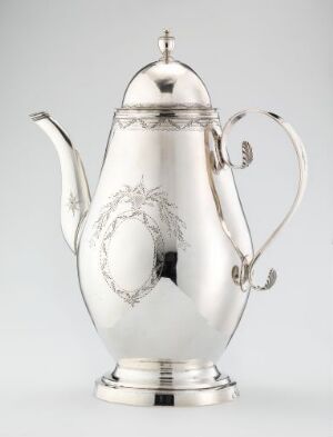  A polished silver teapot with an embossed wreath design, a curved spout, and an insulated handle, set against a neutral gray background.