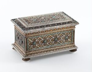  An ornate, rectangular box with intricate inlaid geometric and floral patterns in colors of green, red, blue, and white on a dark background, set against a plain, light backdrop. The box has a slightly domed lid, rounded feet, and appears to be crafted with high precision and attention to detail.