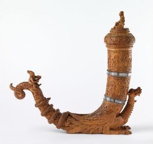  A finely detailed wooden ceremonial horn with a curved shape, featuring a dragon or sea serpent's head and neck at the wider end and encircled by three metallic bands, set against a plain background.