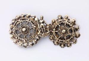  An image of antique, gold-toned cufflinks with an intricate filigree design, adorned with dark gemstones against a light grey background.